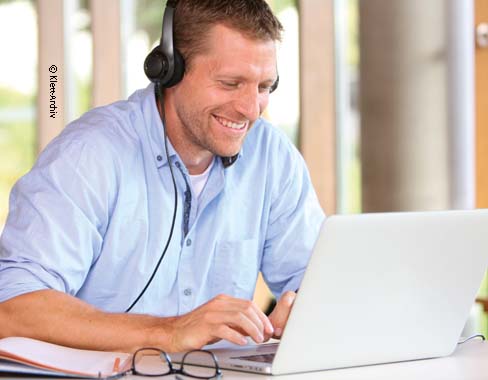 Lehrer_digital Lehrer mit Kopfhörer am Laptop