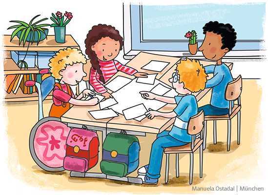 Vier Kinder sitzen im Klassenraum an einem Tisch. Auf der Tischplatte liegen viele Papierseiten. Im Hintergrund steht ein Bücherregal, auf dem Blumen platziert sind.